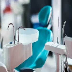 A dentist 's chair and sink in an office.